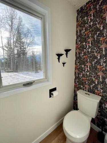 a bathroom with a toilet and a window with birds on the wall at Nell's Mountain Lodge - Arcade Hottub Fire Pit 5 Acres in Golden