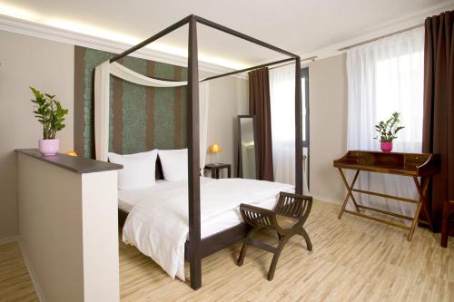 a bedroom with a canopy bed with a chair and a desk at Pension Mariposa in Weimar