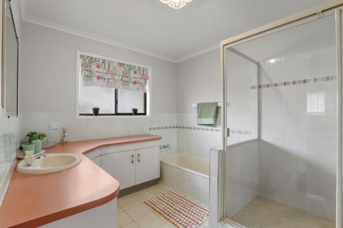 a white bathroom with a sink and a shower at Bren Place, 6, Battery Hill in Caloundra