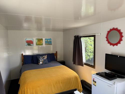 a small bedroom with a bed and a television at Picton's Waikawa Bay Holiday Park in Picton