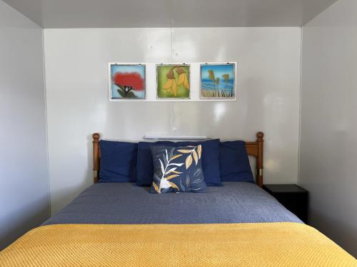 a bedroom with a bed with four pictures on the wall at Picton's Waikawa Bay Holiday Park in Picton