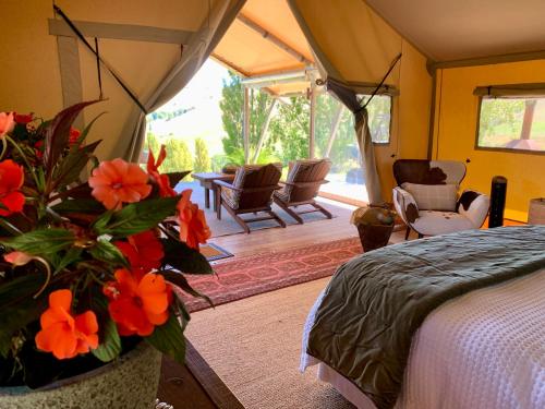 a bedroom with a bed and a vase with flowers at Tuki Glamping in Havelock North
