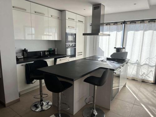 - une cuisine avec un comptoir noir et des tabourets dans l'établissement Résidence White Stone - Bel appartement 3 pièces à proximité de la plage Bonnegrâce MAE-3651, à Six-Fours-les-Plages