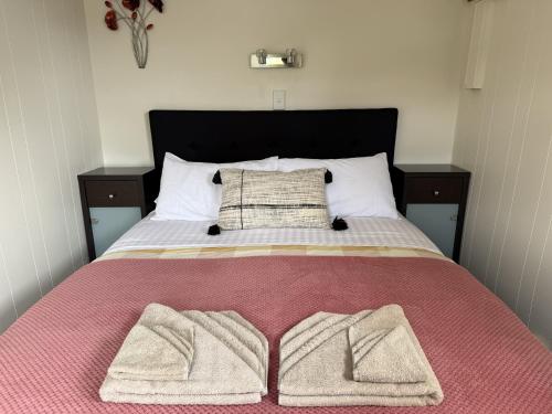 a bed with two blankets and two pillows on it at Picton's Waikawa Bay Holiday Park in Picton