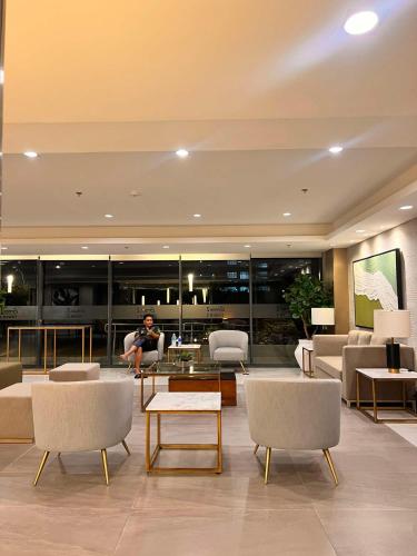 a living room with a man sitting on a couch at SMDC Green 2 Staycation, The Traditional & Modern Fusion Condo in Pasong Bayog
