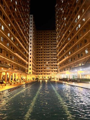 a pool of water in front of two tall buildings at SMDC Green 2 Staycation, The Traditional & Modern Fusion Condo in Pasong Bayog