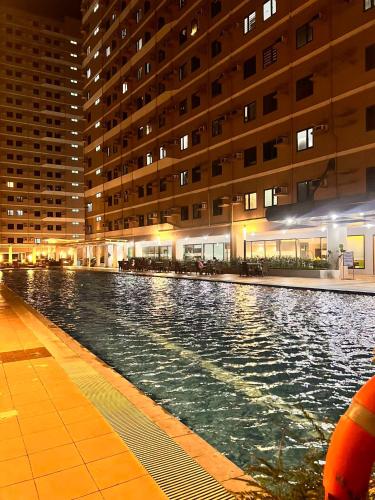 a swimming pool in front of a building at night at SMDC Green 2 Staycation, The Traditional & Modern Fusion Condo in Pasong Bayog