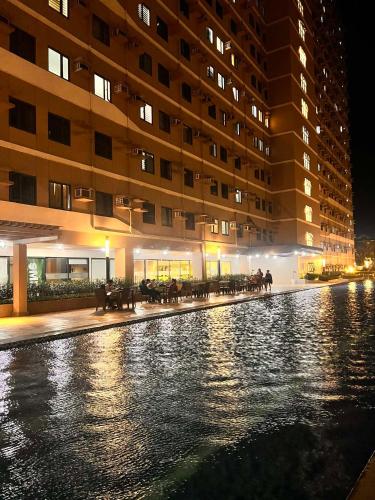 a pool of water in front of a building at night at SMDC Green 2 Staycation, The Traditional & Modern Fusion Condo in Pasong Bayog