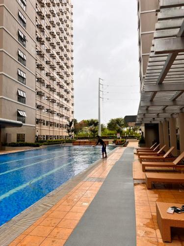 a person standing next to a swimming pool in a building at SMDC Green 2 Staycation, The Traditional & Modern Fusion Condo in Pasong Bayog
