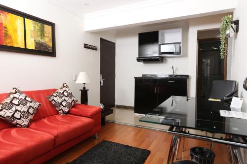 a living room with a red couch and a microwave at Hotel Suites 108 in Bogotá