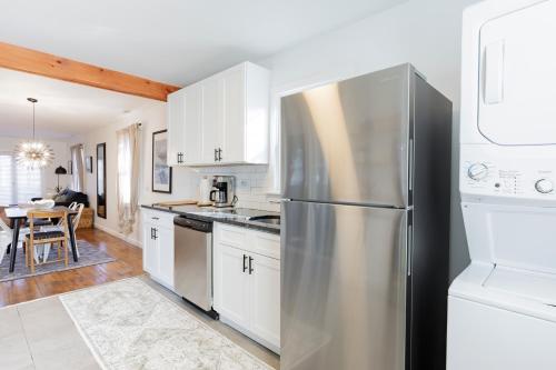 a kitchen with white cabinets and a stainless steel refrigerator at Cozy Beach Cottage Near The Bay in Villas