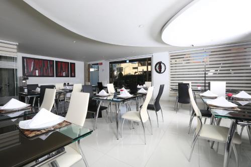 a dining room with tables and white chairs at Hotel Suites 108 in Bogotá