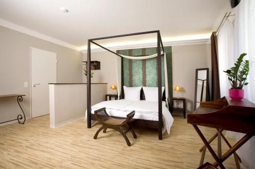 ワイマールにあるPension Mariposaのベッドルーム(天蓋付きベッド、椅子、ピアノ付)
