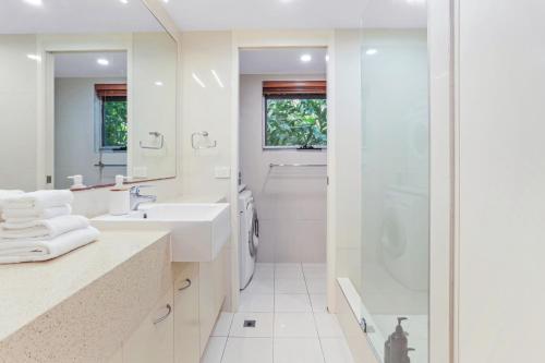 a white bathroom with a shower and a sink at The Cove Noosa - Apartment 6 in Noosa Heads