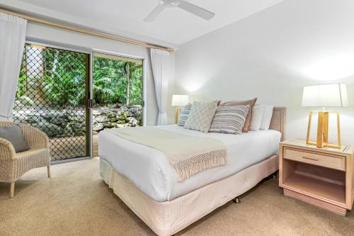 a bedroom with a bed and a chair and a window at The Cove Noosa - Apartment 6 in Noosa Heads