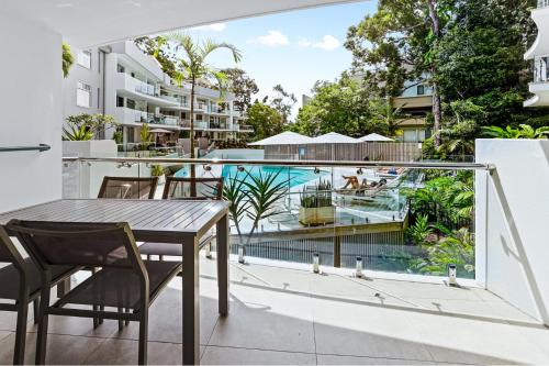 a balcony with a table and chairs and a swimming pool at The Cove Noosa - Apartment 6 in Noosa Heads