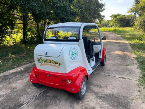 a red and white golf cart parked on a road at RS Phong Riverside Resort in Khon Kaen