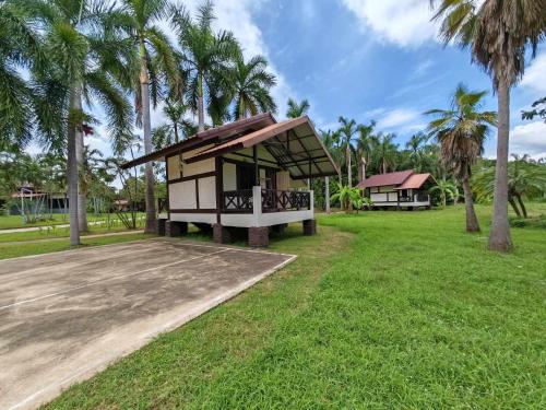 a small building with palm trees in a field at RS Phong Riverside Resort in Khon Kaen