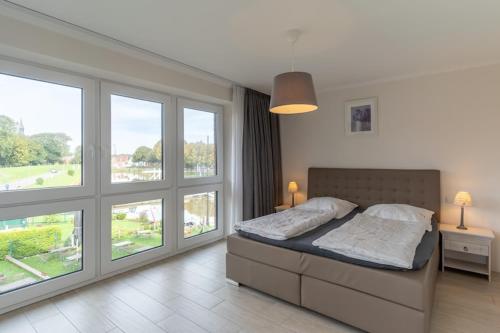 a bedroom with a large bed with windows at Doppelhaushälfte direkt am Hafen von Tönning in Tönning