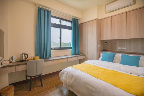 a bedroom with a bed and a desk and a window at 98Guesthouse in Jincheng