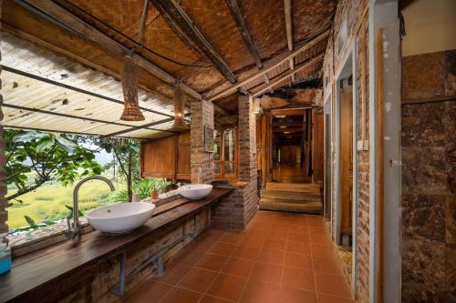 a bathroom with two sinks on a brick wall at Puluong Valley Home in Pu Luong