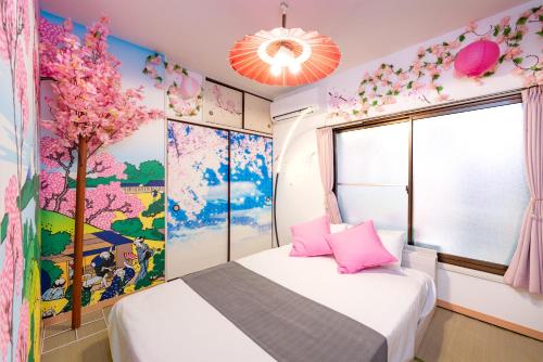 a bedroom with a bed with pink pillows and a tree mural at LEON RESORT HOTEL A 3rooms MAX8people 6min Shinjuku 11min Shibuya 12min walk Ikebukuro LEON RESORT IKEBUKURO traditional Japanese room 池袋 最大8名 in Tokyo