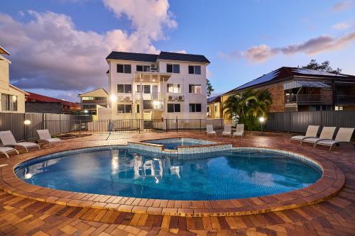 a large swimming pool in a yard with a house at Southport Motel & Apartments in Gold Coast
