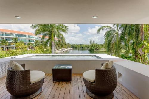 a balcony with two chairs and a swimming pool at Dream House with private Deck in Puerto Aventuras in Puerto Aventuras
