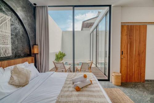 a bedroom with a bed and a balcony with a table at Villa Rosie 1BR Brand New Villa In Kerobokan in Kerobokan