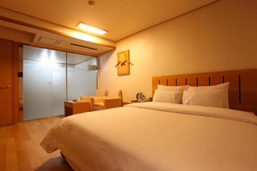 Prince Hotel في سول: غرفة نوم بسرير ابيض كبير وكرسي