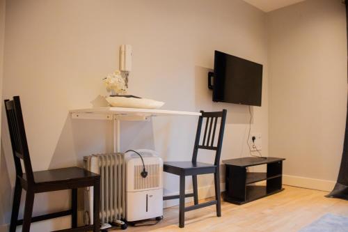 a room with two chairs and a table and a tv at The Chandler Apartments in Leeds