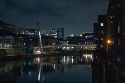 a city at night with a river and buildings at The Chandler Apartments in Leeds