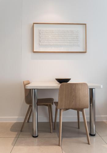a dining room table with two chairs and a picture at On The Beach Noosa Resort in Noosa Heads