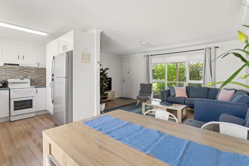 a living room with a blue couch and a kitchen at Rose by the Bay in Tootgarook
