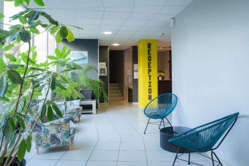 a hallway with chairs and plants in a lobby at Comfort Aparthotel Frejus La Tour de Mare in Fréjus