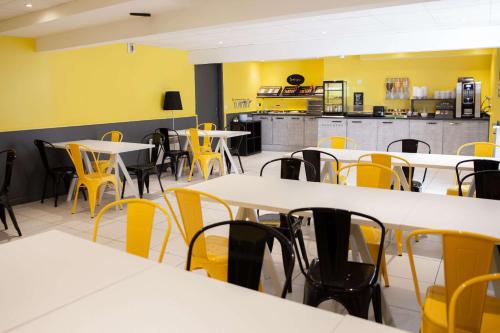 a dining room with tables and yellow chairs at Comfort Aparthotel Frejus La Tour de Mare in Fréjus