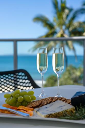 two glasses of wine sitting on a table with food at On The Beach Noosa Resort in Noosa Heads