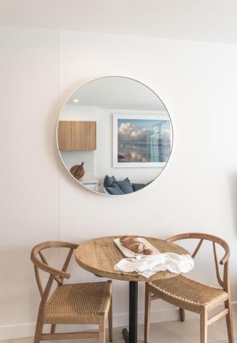a round mirror hangs above a table and two chairs at On The Beach Noosa Resort in Noosa Heads