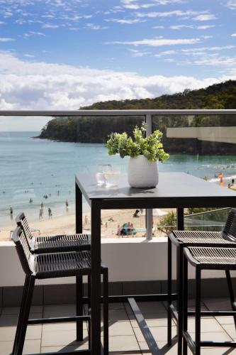 a table on a balcony with a view of a beach at On The Beach Noosa Resort in Noosa Heads
