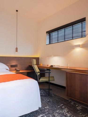 a bedroom with a bed and a desk and a window at Tan Alley Wuzhen Eco and Cultural Community in Tongxiang