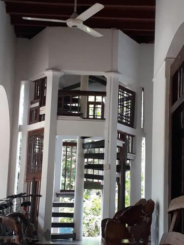 a living room with a ceiling fan and windows at Gatetrees resort in Jaffna