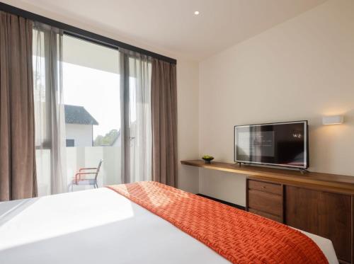 a hotel room with a bed and a tv at Tan Alley Wuzhen Eco and Cultural Community in Tongxiang