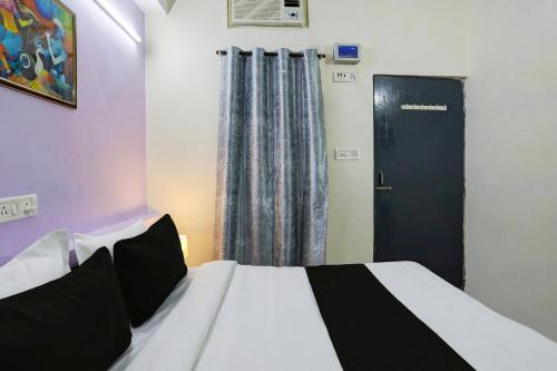a bedroom with a bed with a black door and a window at Hotel O Malviya Nagar Inn in New Delhi