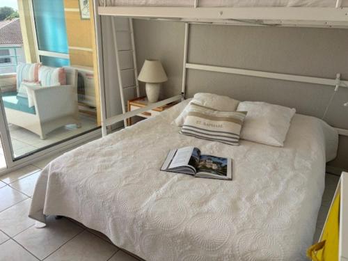 - une chambre avec un lit et un livre dans l'établissement Bel appartement T3 à St Aygulf, climatisé, proche plage, parking privé - FR-1-768-110, à Fréjus