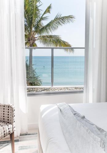 a bedroom with a large window with a view of the ocean at On The Beach Noosa Resort in Noosa Heads