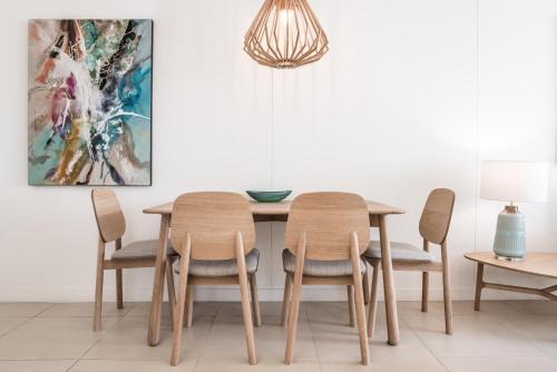 a dining room with a table with chairs and a painting at On The Beach Noosa Resort in Noosa Heads