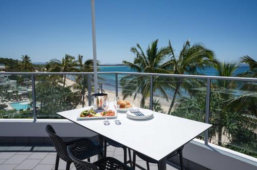 a white table with a plate of food on a balcony at On The Beach Noosa Resort in Noosa Heads