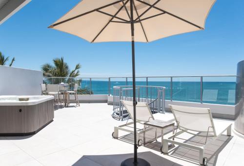 a patio with chairs and an umbrella and the ocean at On The Beach Noosa Resort in Noosa Heads