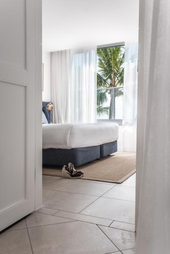 a bedroom with a bed and a palm tree at On The Beach Noosa Resort in Noosa Heads