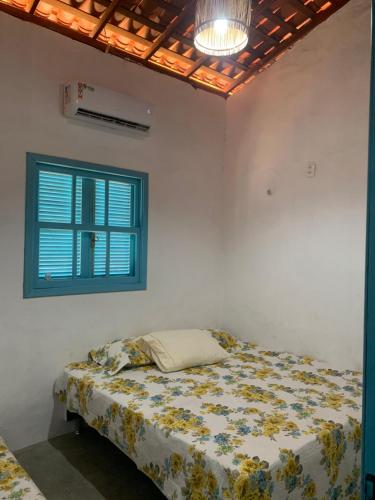 ein Bett in einem weißen Zimmer mit einem Fenster in der Unterkunft Cajumar in Cajueiro
